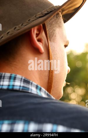 Ein junger Mann mit einem Cowboyhut blickt in die Ferne in den Himmel und fängt die Essenz des Abenteuers und den Geist des Wilden Westens ein. Die untergehende Sonne Stockfoto