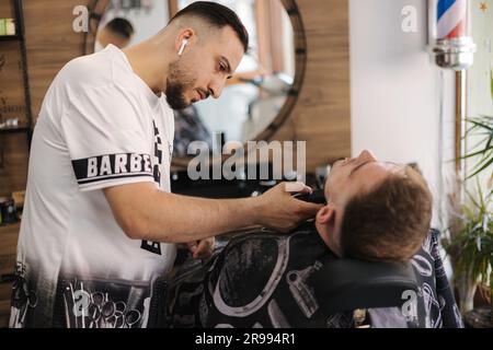 Rückansicht eines Friseursalons, der dem männlichen Klienten Haare schneidet. Friseursalon Stockfoto