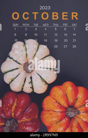 Oktober 2023 Kalender und Kürbisse auf schwarzem Papphintergrund. Stockfoto