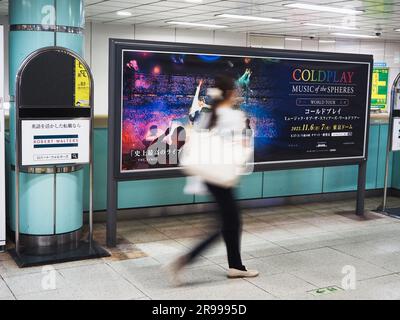 TOKIO, JAPAN - 14. Juni 2023: Person geht an einem Poster vorbei für ein Coldplay-Konzert im Tokyo Dome in der U-Bahn-Station Roppongi. Stockfoto
