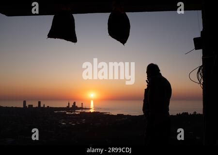 Batumi, Georgia. 24. Juni 2023. Ein Mann steht auf seinem Balkon bei Sonnenuntergang vor dem Hintergrund der Hafenstadt am Schwarzen Meer. Kredit: Sebastian Kahnert/dpa/Alamy Live News Stockfoto