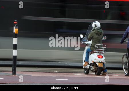 Eine Straßenszene in Eindhoven mit einem Bus und einer Frau auf einem Roller. Stockfoto