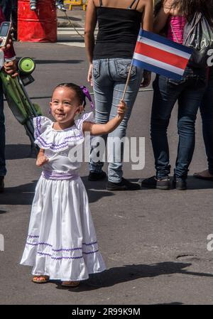 Ein junges Mädchen in traditioneller Kleidung hält stolz eine Costa-ricanische Flagge bei einer Feier zum Unabhängigkeitstag in San José, Costa Rica. Stockfoto