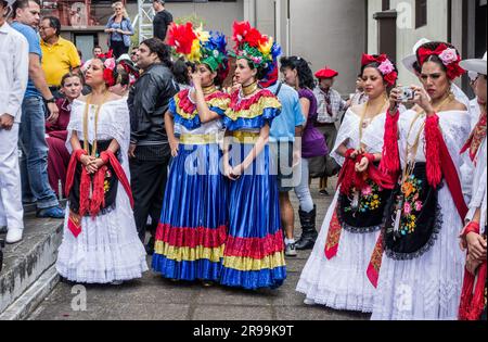 Junge Frauen in bunten, traditionellen Kleidern warten darauf, auf der Bühne eines Volksfestivals in San José, Costa Rica, aufzutreten. Stockfoto