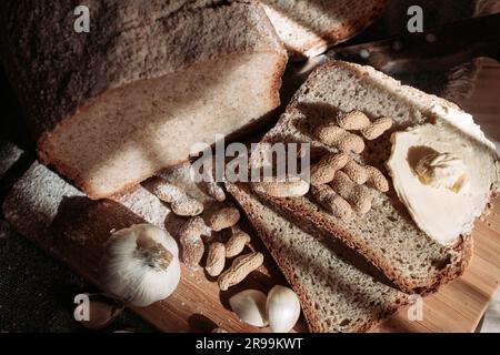 Draufsicht auf ein hausgemachtes Weizenmehlbrot mit Erdnüssen, Butter und Knoblauch auf dem Tisch Stockfoto