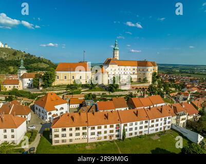 Aus der Vogelperspektive sehen Sie das restaurierte barocke Schloss Mikulov in Südböhmen, auch Nikolsburg genannt, mit mittelalterlichen Türmen, die von kommunistischen Häusern umgeben sind Stockfoto
