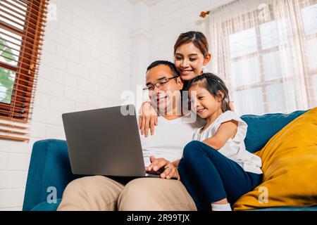 Familienvater, Mutter und Tochter nutzen Laptop und surfen im Internet Stockfoto