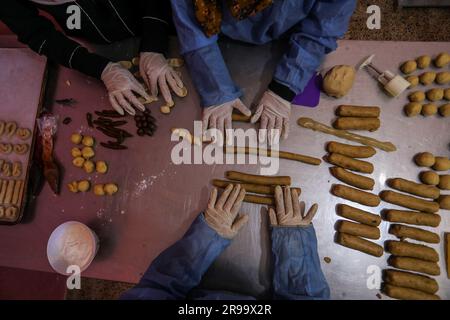 Palästinensische Frauen machen vor Eid Al-Adha in ihrem Haus im Gazastreifen am 25. Juni 2023 Kekse, die als „Eid Cakes“ bezeichnet werden. Stockfoto