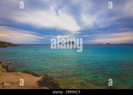 Eine atemberaubende Küstenlandschaft mit mehreren Booten, die nahe einer Küste unter dem blauen Himmel vor Anker liegen Stockfoto