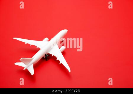 Weißes Passagierflugzeugmodell auf rotem Hintergrund, Reisekonzept. Stockfoto