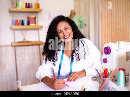 Fröhliche Schneiderin Skizziert Kleidungsmuster Im Nähmaschinenbereich Stockfoto