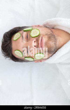 Junger Mann mit Gesichtsmaske im Spa-Salon Stockfoto
