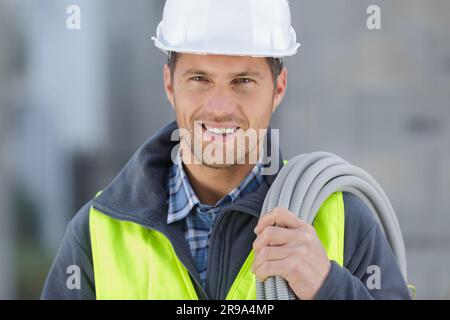 Glücklicher männlicher Baumeister, der Kabel hält Stockfoto