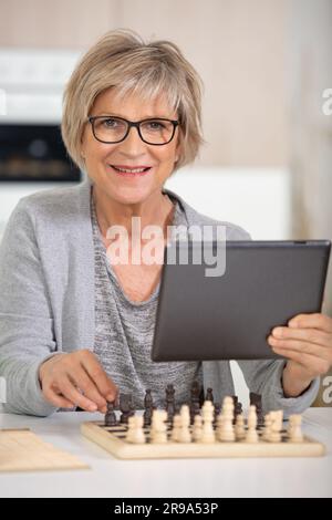 Ältere Frau, die Schachttabletten spielt Stockfoto