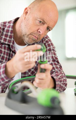 Ein kahlköpfiger Mann, der einen Gartenschlauch zusammenbaut Stockfoto