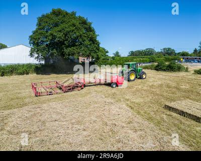 Heuernte mit Ballengreifer von Landmaschinen im Sommer, Draufsicht. Stockfoto