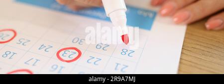 Weibliche Hand markiert Daten in Kalender mit rotem Marker Stockfoto
