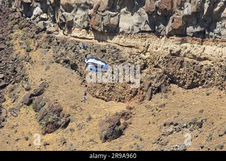 An einem sonnigen Tag in Twin Falls, Idaho, springt ein Base Jumper mit Fallschirmen den Canyon hinunter. Stockfoto