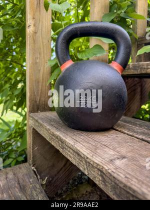 Schwere Eisenkugel für Krafttraining auf rustikalen Holztreppen im Hinterhof, Heimtrainer und Fitnesskonzept Stockfoto