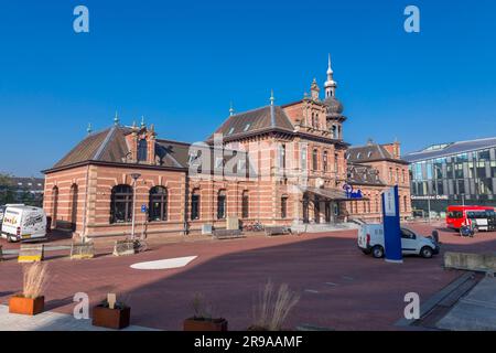 Delft, Niederlande, 9. Oktober 2021: Der alte Bahnhof von Delft, das heutige Restaurant Pavarotti neben dem neuen Bahnhof und dem Rathaus von Delft, Th Stockfoto