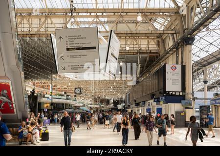 Leute, die durch die Londoner Waterloo-Bahnhofshalle laufen und nach Zugzeiten suchen. UK. Konzept: Fahrkartenpreise, Bahnreisen, Pendler Stockfoto