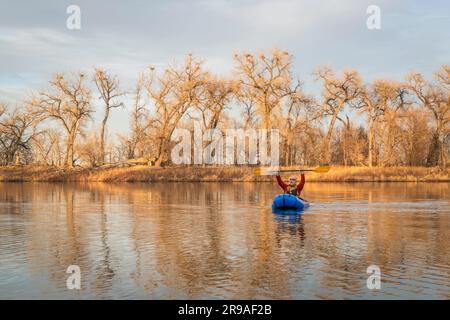 Älterer Rüde paddelt ein aufblasbares Packraft auf einer ruhigen see mit Reiher Rookery im frühen Frühjahr im Norden von Colorado Stockfoto