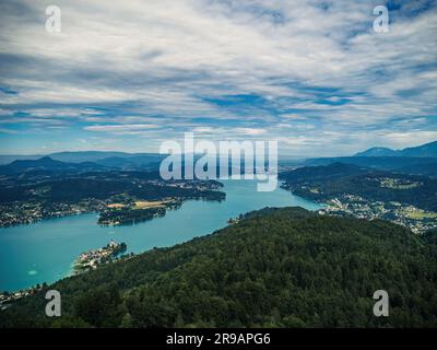 Blick aus der Vogelperspektive auf den Worthersee (Wörthersee) und Klagenfurt in Kärnten, Österreich, vom Aussichtsturm Pyramidenkogel bei bewölktem Sommerwetter Stockfoto