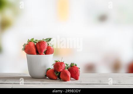 Rote Erdbeeren in eine weiße Tasse auf einem Holztisch Stockfoto
