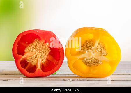 Rote und gelbe Paprika mit Samen auf einem Holztisch im Garten Stockfoto