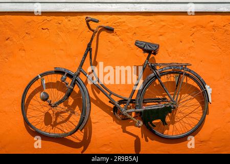 Oldtimer Fahrrad hängen an einer Wand in der Farbe orange Stockfoto