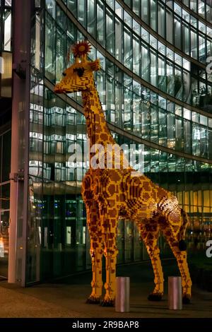 Berlin, Deutschland - 17. DEZ. 2021: Riesige Giraffenstatue vor dem Legoland Discovery Center, Nachtaufnahme in Berlin. Stockfoto