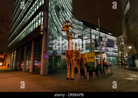 Berlin, Deutschland - 17. DEZ. 2021: Riesige Giraffenstatue vor dem Legoland Discovery Center, Nachtaufnahme in Berlin. Stockfoto