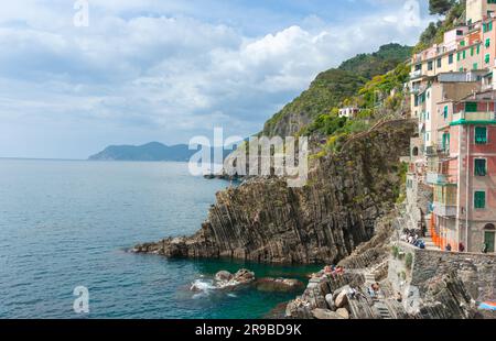 Riomaggiore Italien 26 2011. April; Felsklippe am Meeresrand mit zerklüftetem, verwittertem vertikalem Muster, mit Springern, die ins Meer stürzen Stockfoto