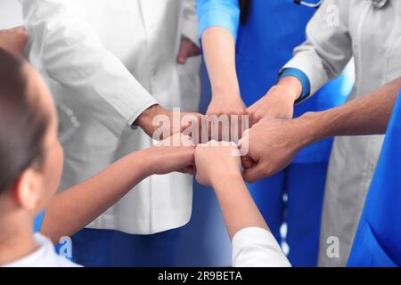 Ärzteteam, das die Hände drinnen zusammenfasst, Nahaufnahme Stockfoto