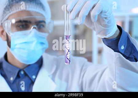 Genforschung. Wissenschaftler, der das Reagenzglas mit Flüssigkeit hält und die DNA-Struktur im Labor darstellt, selektiver Fokus Stockfoto