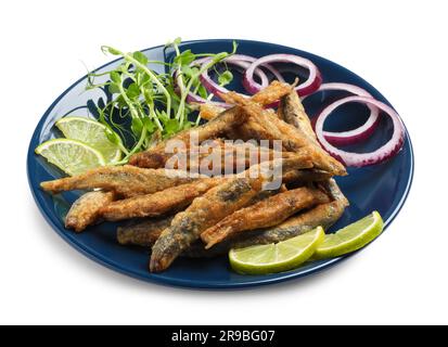 Teller mit köstlichen gebratenen Sardellen, Limettenscheiben, Mikrogreens und Zwiebelringen auf weißem Hintergrund Stockfoto