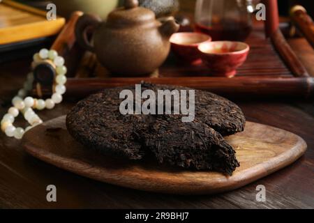 Gebrochener, scheibenförmiger pu-erh-Tee auf einem Holztisch Stockfoto