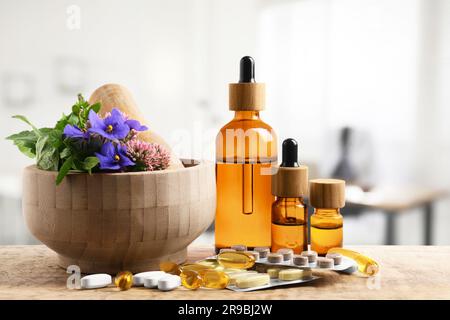 Mörtel mit frischen Kräutern, Flaschen mit Extrakten und Pillen auf Holztisch in der Arztpraxis Stockfoto