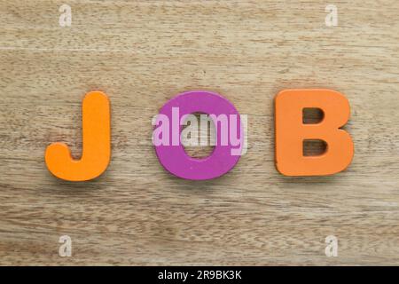 Holzbuchstaben bilden ein Wort „Job“. Arbeitssuchkonzept auf Holzhintergrund. Stockfoto