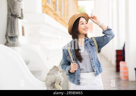 Porträt einer asiatischen Reisenden, die auf dem Fußweg des Tempels spaziert, während sie zurück in Bangkok, Thailand, Südostasien lächelt - eine Frau, die allein mit dem Rucksack unterwegs ist - mit Kopierbereich Stockfoto
