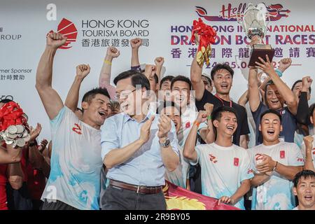 John Lee Ka-Chiu, der Chief Executive von Hongkong, steht mit den Teilnehmern der Drachenbootrennen auf dem Podium. Die Hong Kong International Dragon Boat Races werden vom Hong Kong Tourism Board am 24. Juni und am 25. Juni 2023 im Victoria Harbour, Hongkong, abgehalten. Die Veranstaltung zieht Teams aus verschiedenen Ländern an, darunter Thailand, Kanada, China, Australien, Und vieles mehr. Tausende von Menschen versammeln sich entlang der Ostküste von Tsim Sha Tsui, um die aufregenden Drachenbootrennen zu beobachten. Am 25. Juni nimmt John Lee Ka-chiu, der Chief Executive von Hongkong, an der Preisverleihung für das Drachenboot Teil Stockfoto