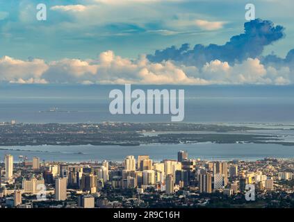 Das Licht der untergehenden Sonne badet die Hochhäuser in der Hauptstadt Cebu, mit Blick über den Meereskanal zur Mactan Island, dramatische Wolken Stockfoto