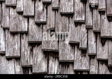 Nahaufnahme des Texturhintergrunds einer Wand, die mit großen Schindeln aus Holz bedeckt ist Stockfoto