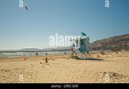 Pismo Beach, Kalifornien, USA - 17. Juni 2023. Breiter Sandstrand und Rettungsschwimmturm, mit Bergen und klarem blauen Himmel im Hintergrund, Kalifornien Stockfoto