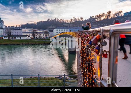 Salzburg, Österreich - 27. Dezember 2021: Junge Frau macht ein Foto von der Makartsteg-Brücke (Love Locks Bridge) über die Salzach in Salzburg, Österreich Stockfoto