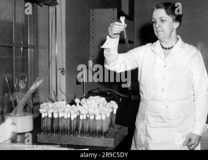 Washington, D.C.: c. 1933 Senior Bakteriologe Dr. Alice C. Evans aus den USA Der Gesundheitsdienst hält ein Reagenzglas mit einer frischen Kolonie von unförmigen Fieberkeimen, für die sie eine Heilung sucht. Stockfoto