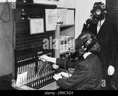 London, England: 1939 Telefonisten im Westminster Hospital tragen spezielle Gasmasken mit Mikrofonbefestigungen, damit sie während der Luftwaffe-Luftangriffe weiterarbeiten können. Stockfoto