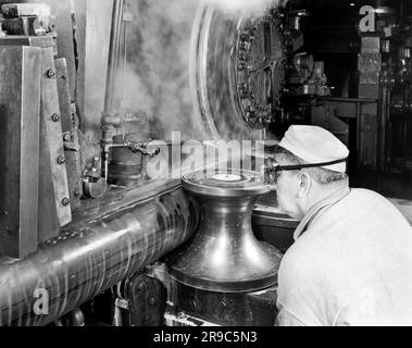 Vereinigte Staaten: c. 1950 Ein Mann mit Schutzbrille, der an einer großen industriellen Schleifmaschine arbeitet. Stockfoto