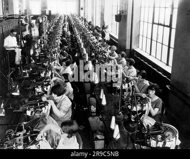 Philadelphia, Pennsylvania: ca. 1922 Eine Szene in einer Frauenfabrik für Seidenstrümpfe. Die Frauen arbeiten an den Nähmaschinen, die die Nähte hinten in den Strumpf nähen. Stockfoto