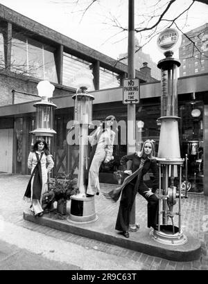 Chicago, Illinois: 3. Januar 1970 drei Verkäuferinnen Modellkleidung aus der Garage Boutique mit 1910 Zapfsäulen am Eingang. Stockfoto